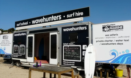 Large format exterior vinyl graphics applied to a mobile trailer unit on Polzeath beach, featuring high-contrast branding and chalkboard elements