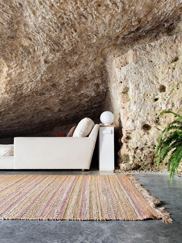 Rough cave walls and modern white furniture and woven rugs