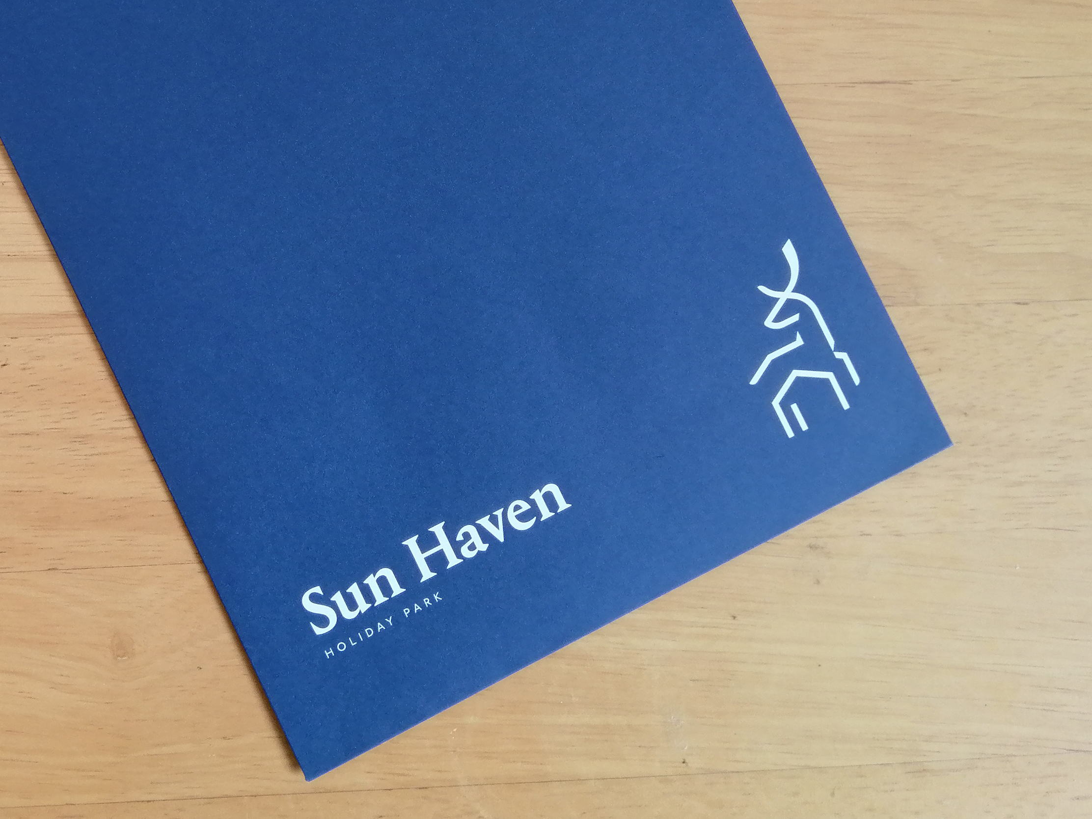Deep blue Sun Haven welcome pack envelope with Lovat Parks branding