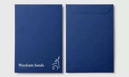 Deep blue Waxham Sands welcome pack envelope shown front and back