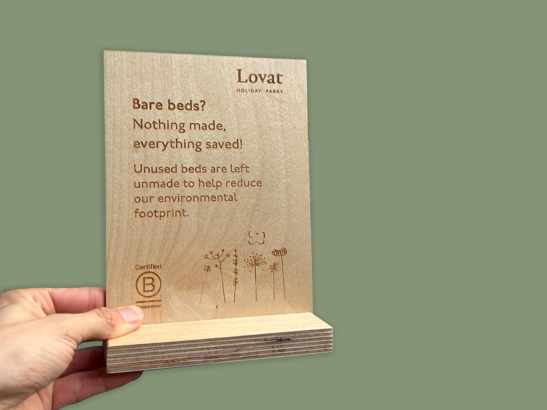 Laser-engraved wooden sign for Lovat Holiday Parks explaining their eco-friendly 'bare beds' initiative.